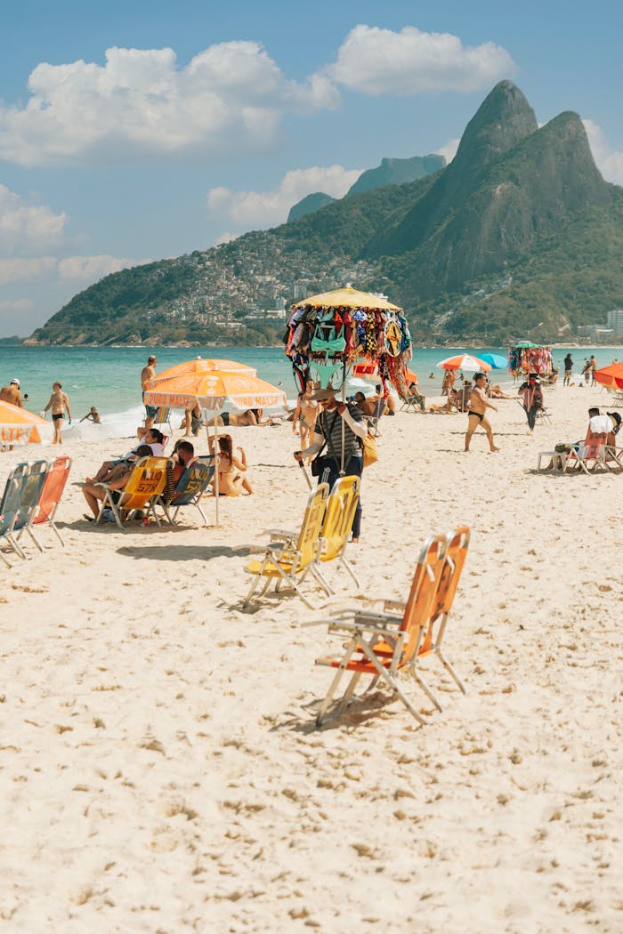 Sunny day at Ipanema Beach, Rio, with vibrant umbrellas and picturesque mountains.